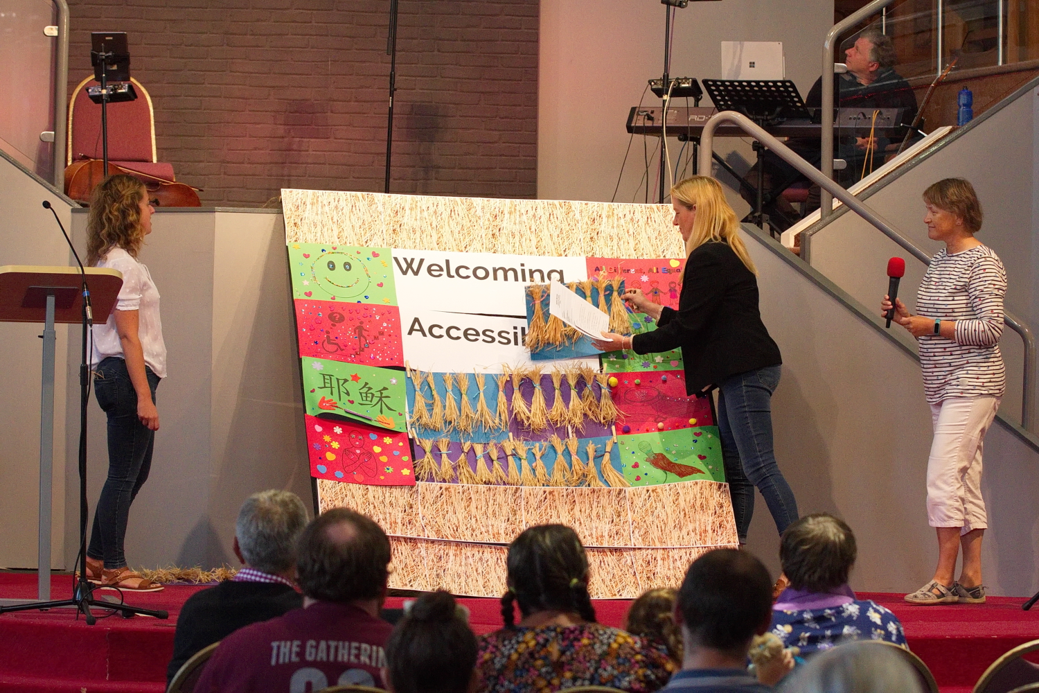 A photo of the 'roof tile' display, at Upton Vale Baptist Church service in 2022, with rooftiles being removed by two ladies are to reveal the words ‘Welcoming, Accessible’.